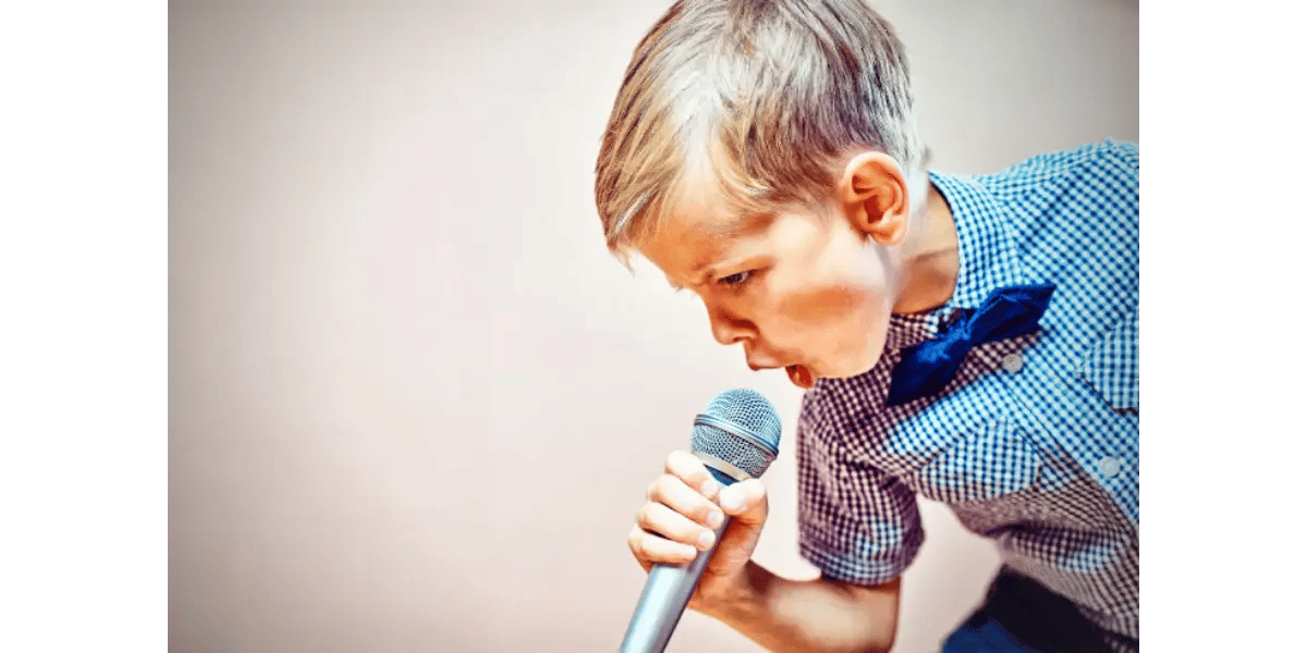 Young boy singing into a microphone to represent the chest voice register and vocal power techniques.
