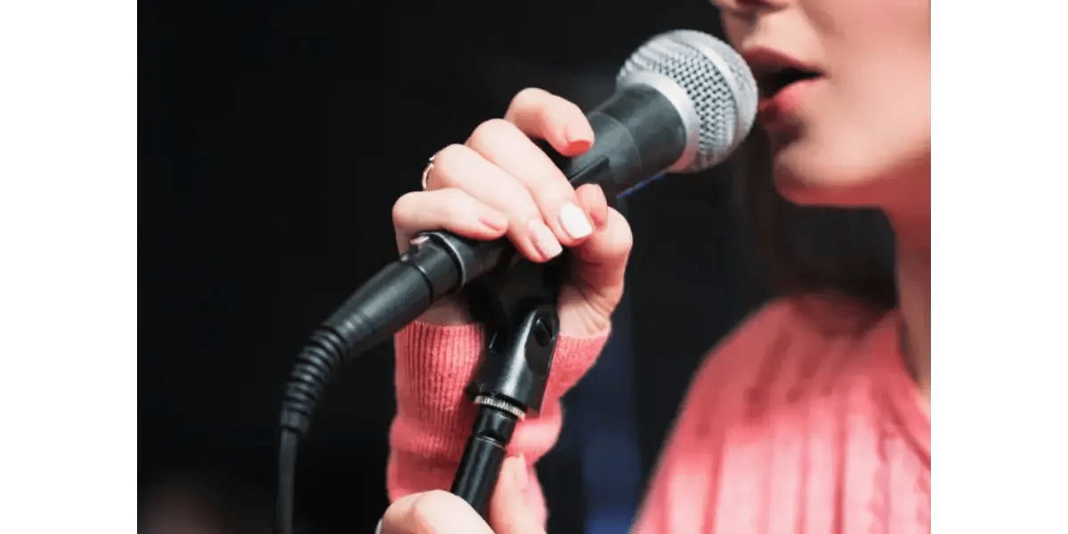 A singer holding a microphone, representing the lightness and flexibility of falsetto dominated registration.