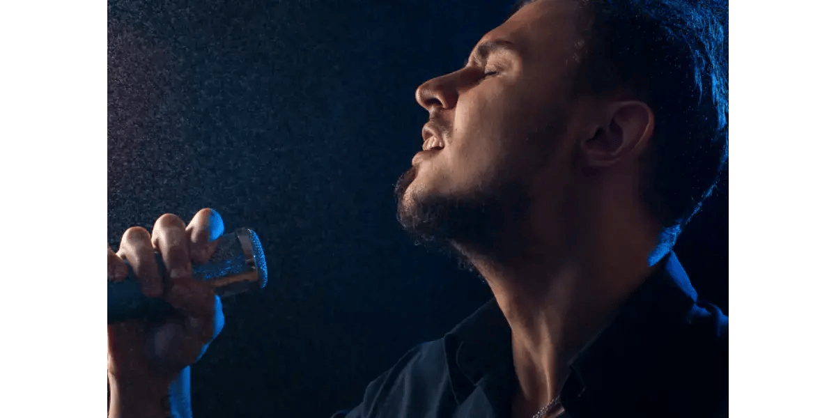 Male singer performing vocal exercises with open throat posture to develop sympathetic resonance and vocal strength.