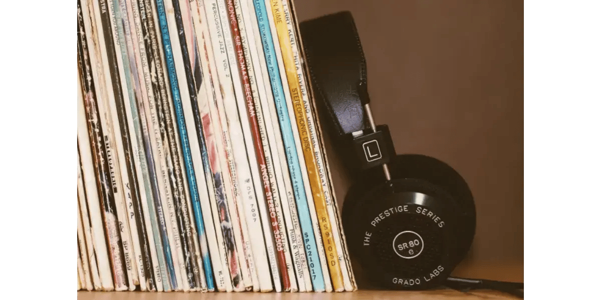 Vintage vinyl records stored on a wooden shelf next to audio headphones