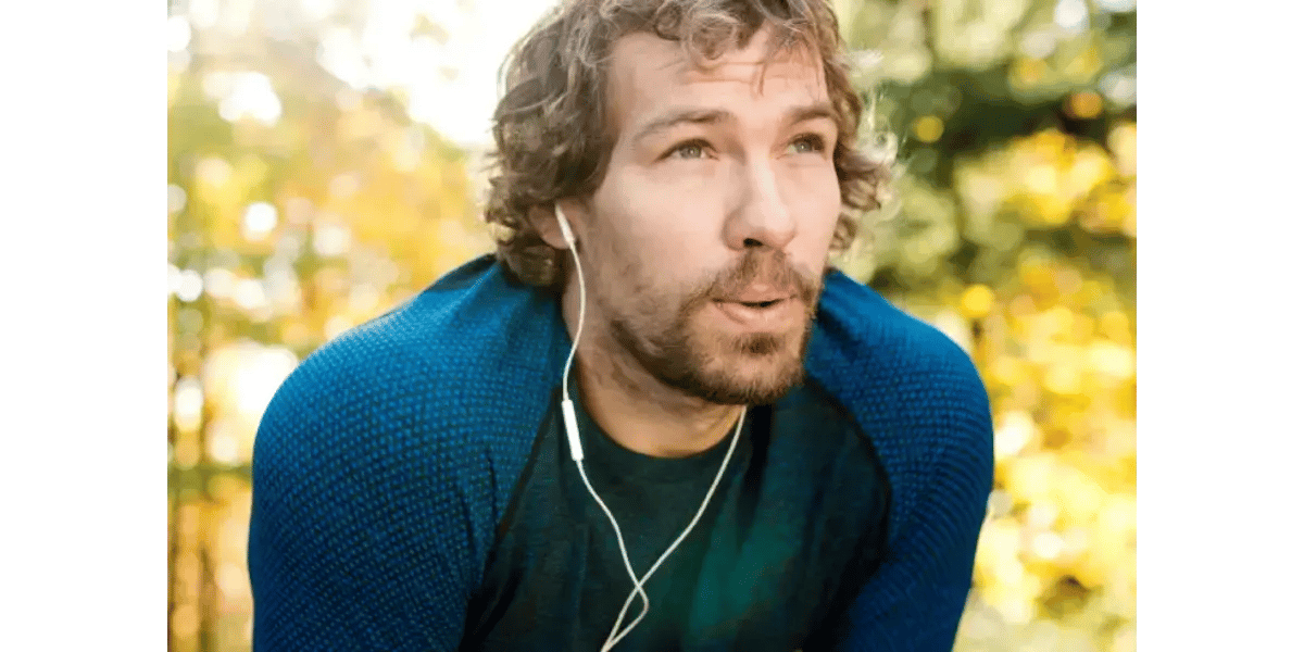 A man outdoors with earphones taking a breath, representing healthy breathing techniques and breath support for singers.