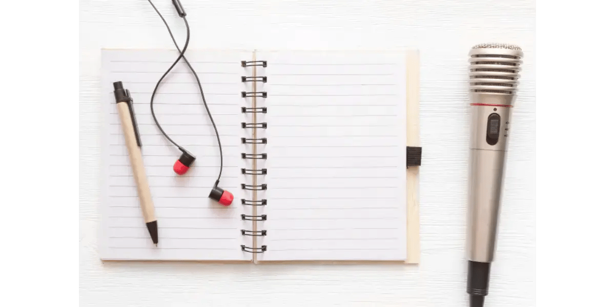 A notebook, pen, and earbuds set up on a desk, ready for an online singing lesson.
