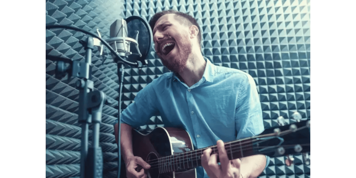 A male vocalist singing into a studio microphone, demonstrating breath support and vocal control.