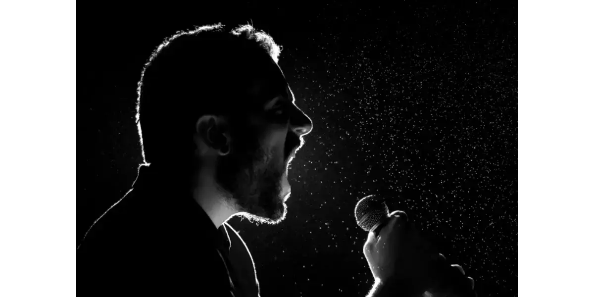 A silhouette of a singer at a microphone, illustrating the concept of controlled breathing and tension-free vocal mechanics.