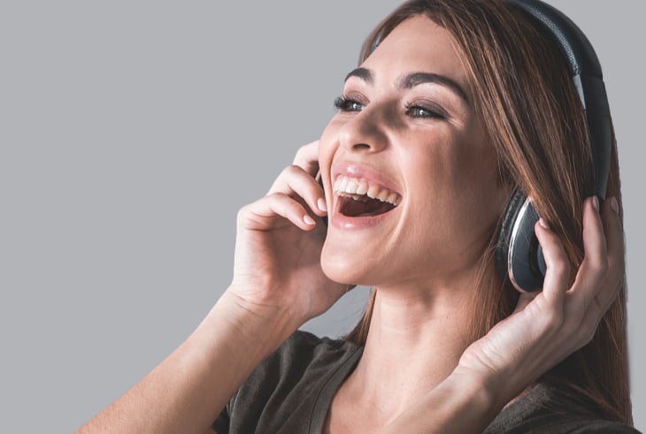 Female singer holding her cheeks to practice lip trill vocal warm-up exercises in a studio.