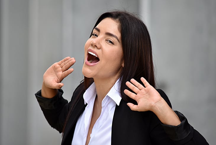 Female singer practicing open throat vocal technique with hand gestures in a studio.