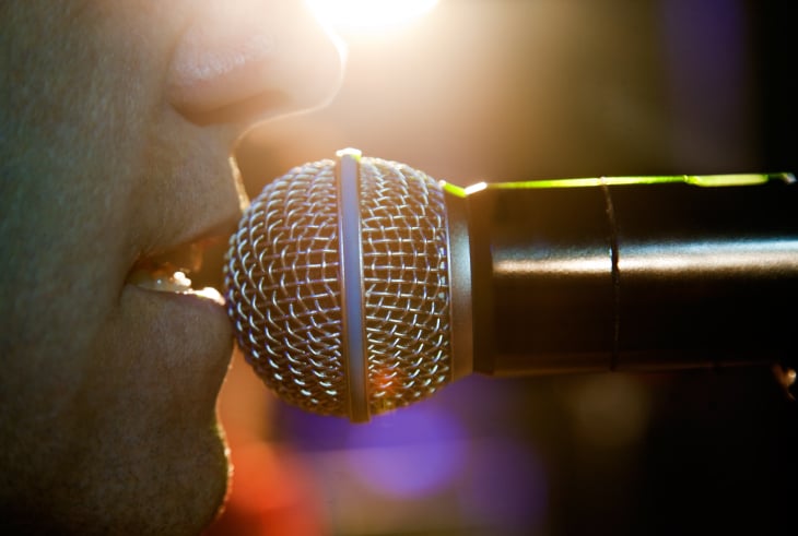 Vintage studio microphone illuminated on stage symbolizing vocal resonance and upper register technique.