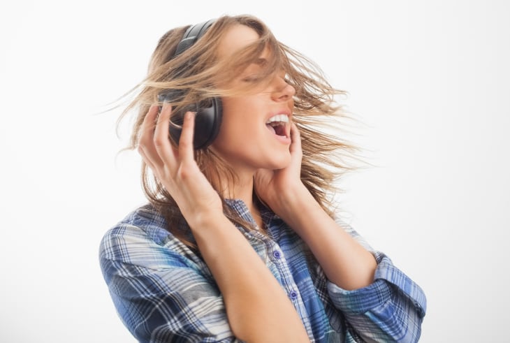 Female singer wearing headphones practicing vocal exercises in a studio to fix vocal wobble.