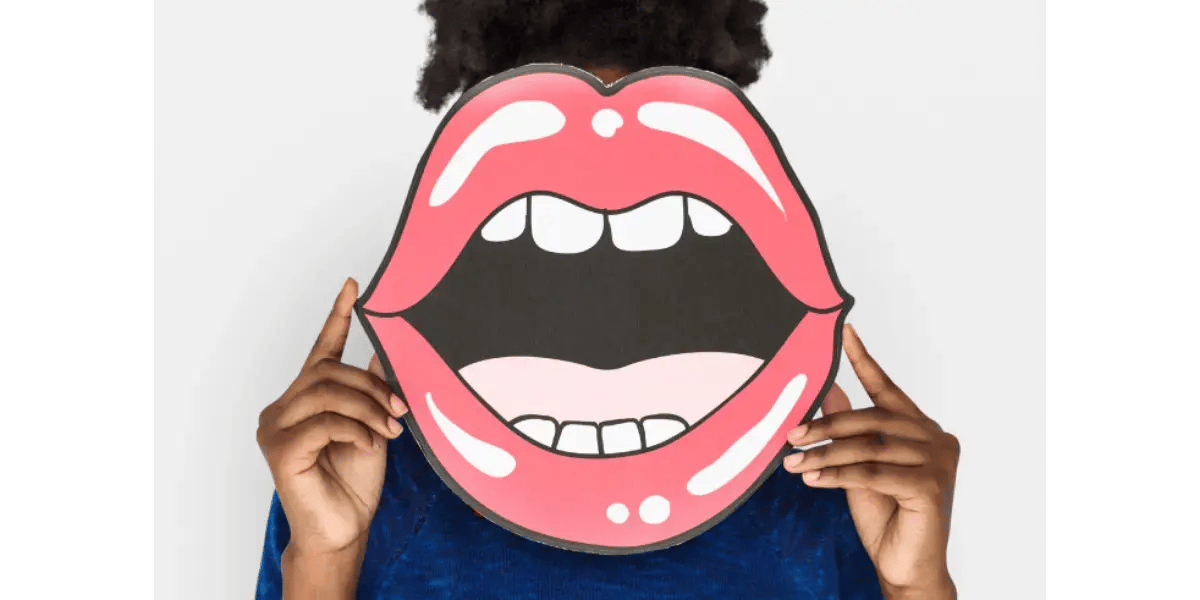 A singer holding a large open mouth cutout, representing the concept of vocal resonance and getting "stuck in the mouth" while singing.