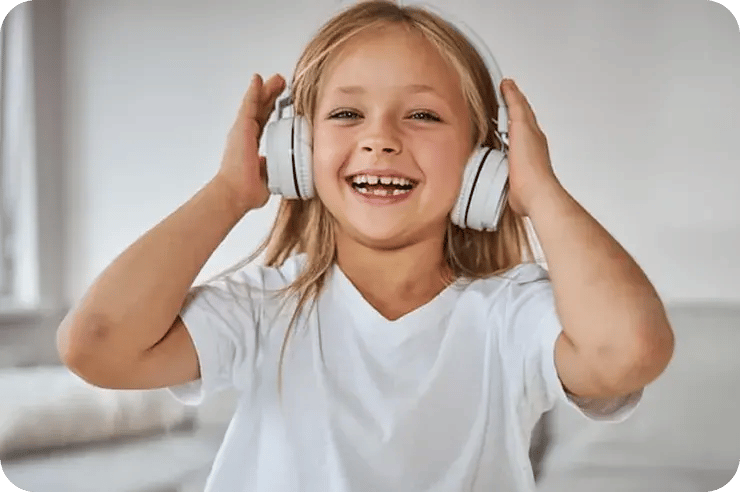 Young girl wearing headphones smiling during an online kids singing lesson.