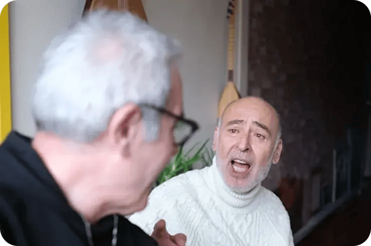 Senior man smiling and singing with an instructor during a vocal lesson.