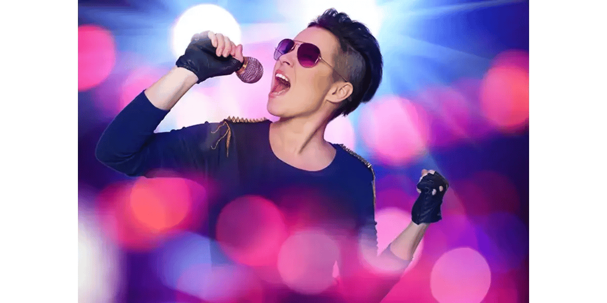 A stylish female vocalist wearing sunglasses and fingerless gloves holding a microphone close to her mouth while singing on stage, illuminated by vibrant pink, blue, and purple bokeh background lights.