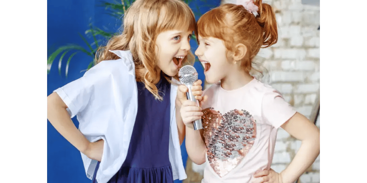 Two young children happily singing into a microphone, representing kids' singing lessons and vocal health.