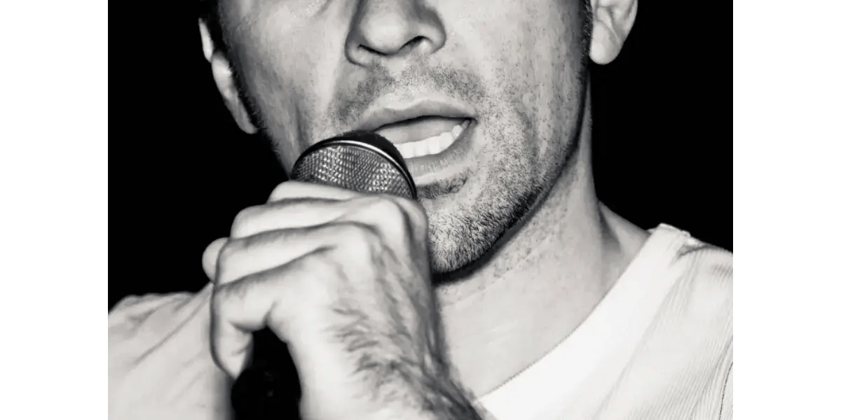 A close-up of a vocalist singing into a microphone, representing vocal resonance and chest voice mechanics.