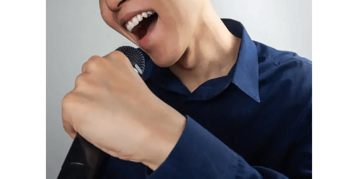 A singer touching their larynx to feel vocal cord vibrations while practicing healthy vocal techniques.