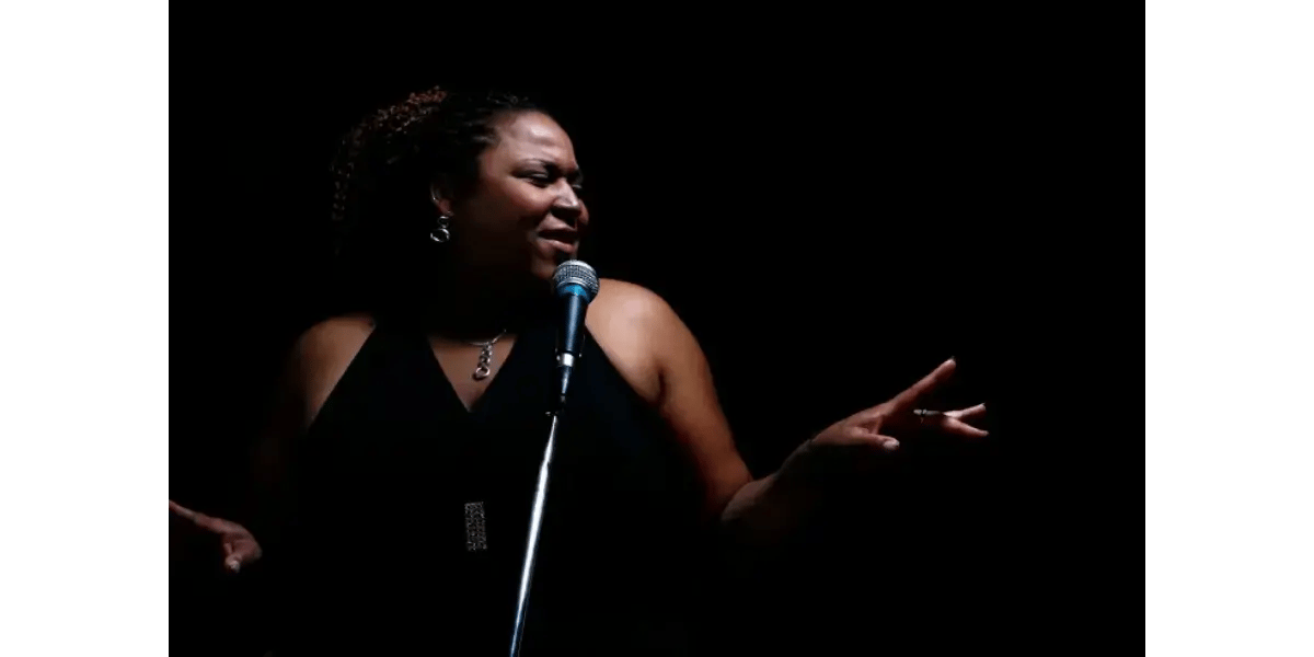 A singer performing passionately into a microphone on a dark stage, representing the power and control of a developed falsetto voice.