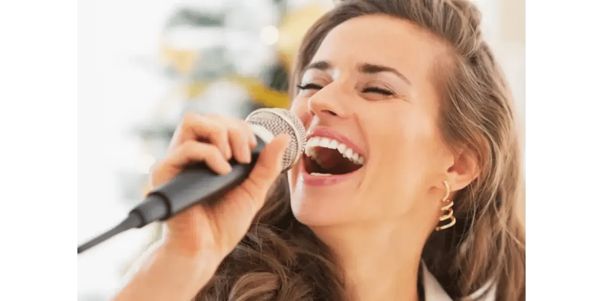 A happy, relaxed singer performing with a microphone, demonstrating a free and natural vocal technique.