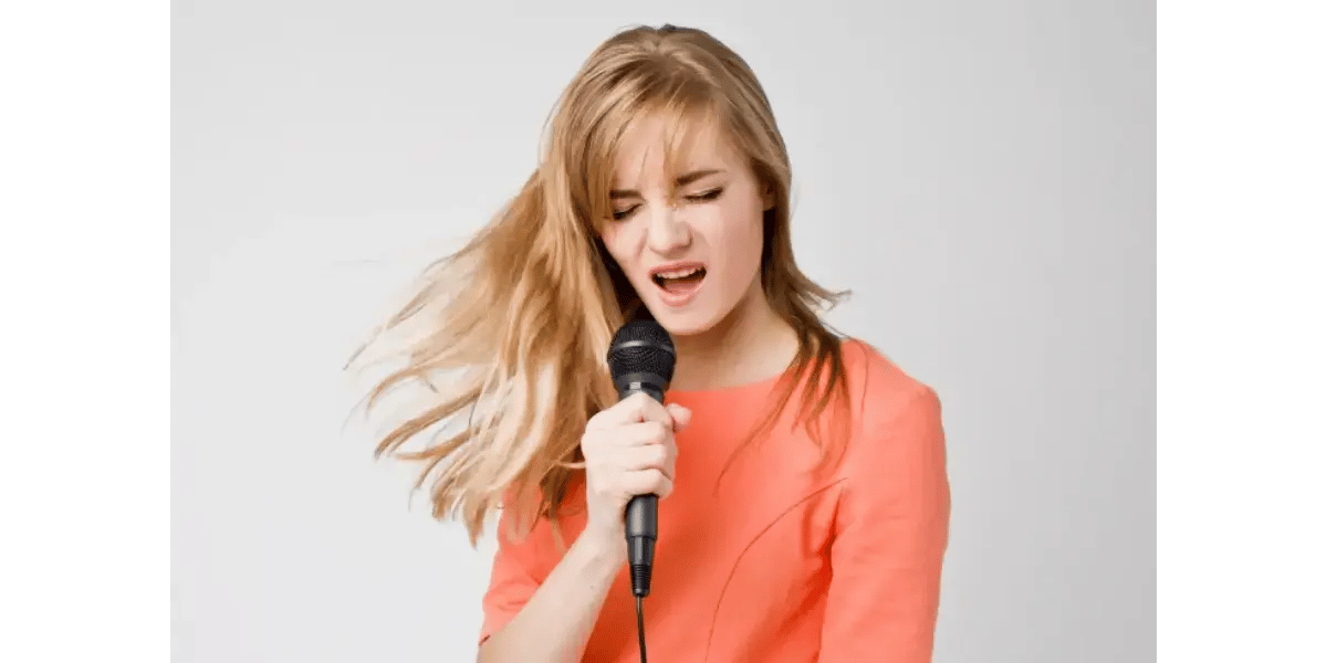 A singer performing energetically into a microphone, representing vocal stamina and physical energy in singing.