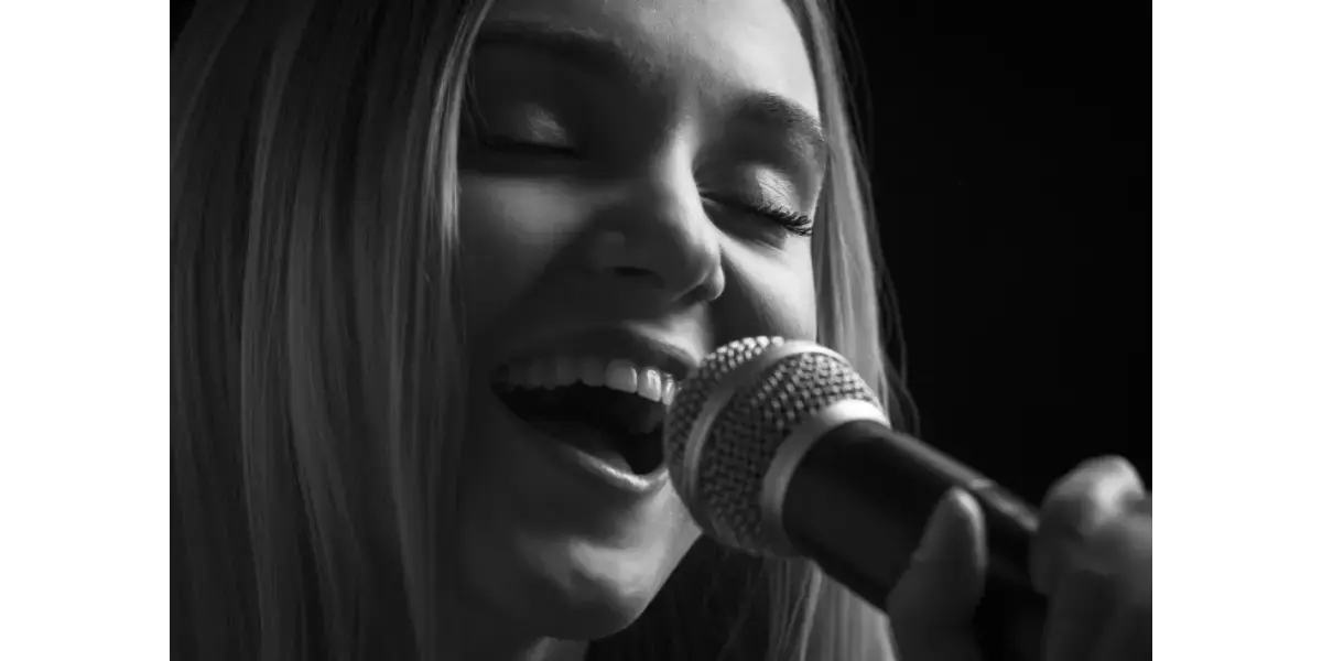 A vocalist singing powerfully into a microphone, representing smooth vocal coordination and navigating the passaggio.