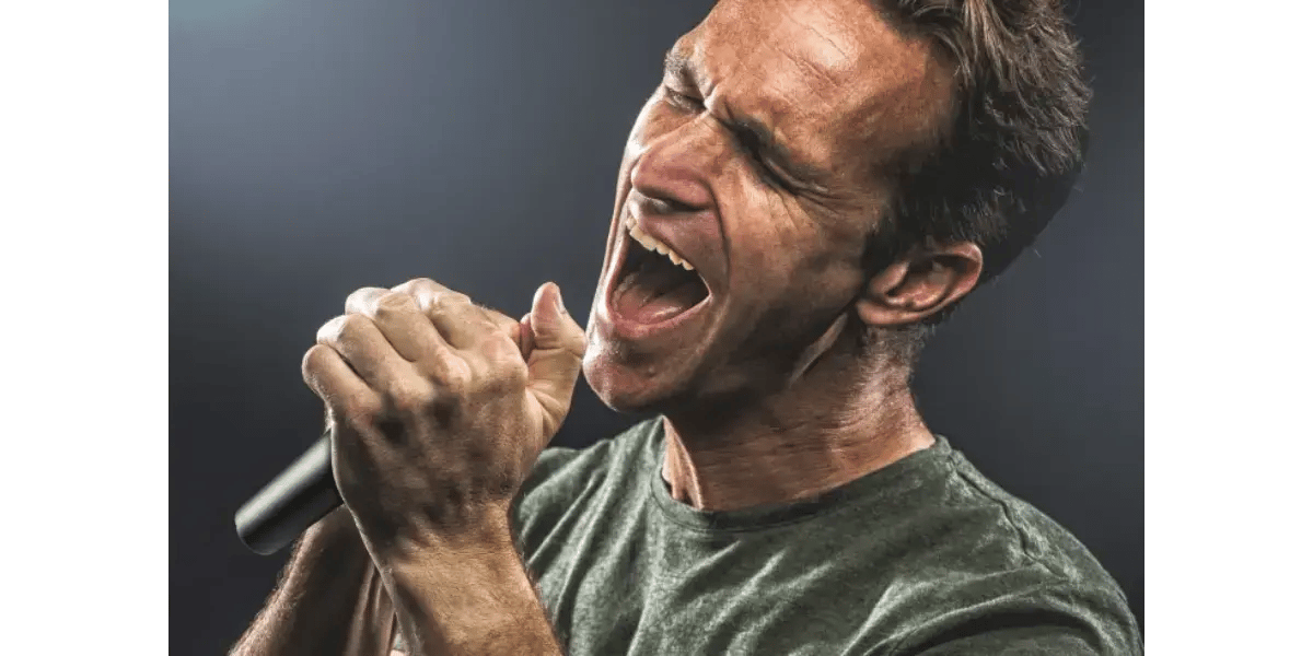 A male vocal student straining to hit high notes and pushing volume with a heavy chest voice into a microphone.