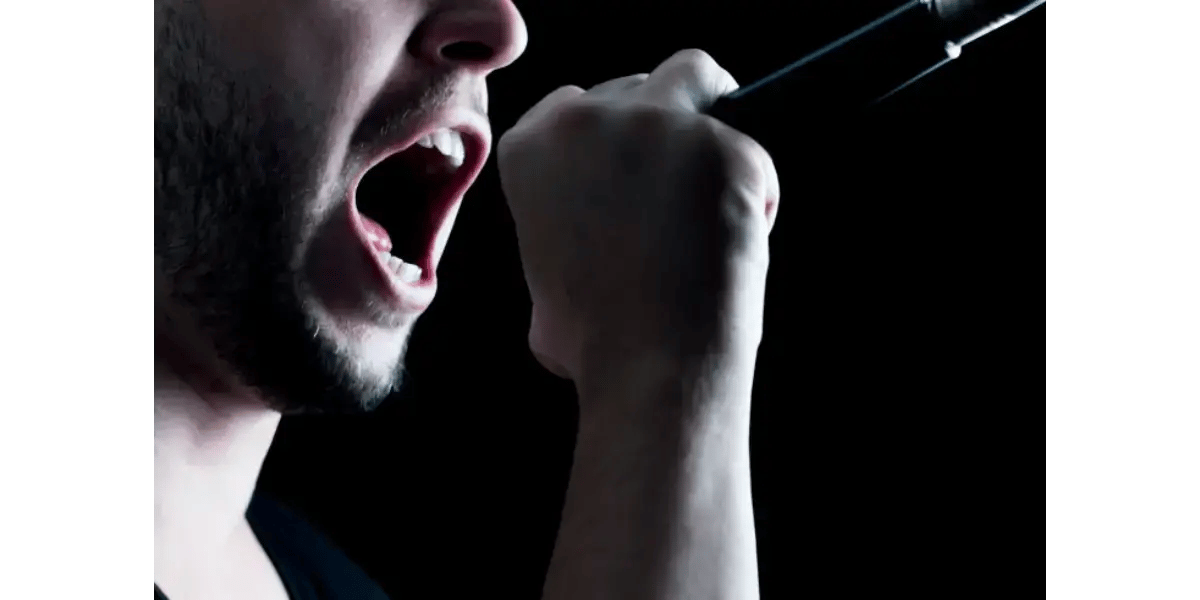 A vocalist singing intensely in profile, representing the vocal agility and strong cord closure developed through staccato exercises.