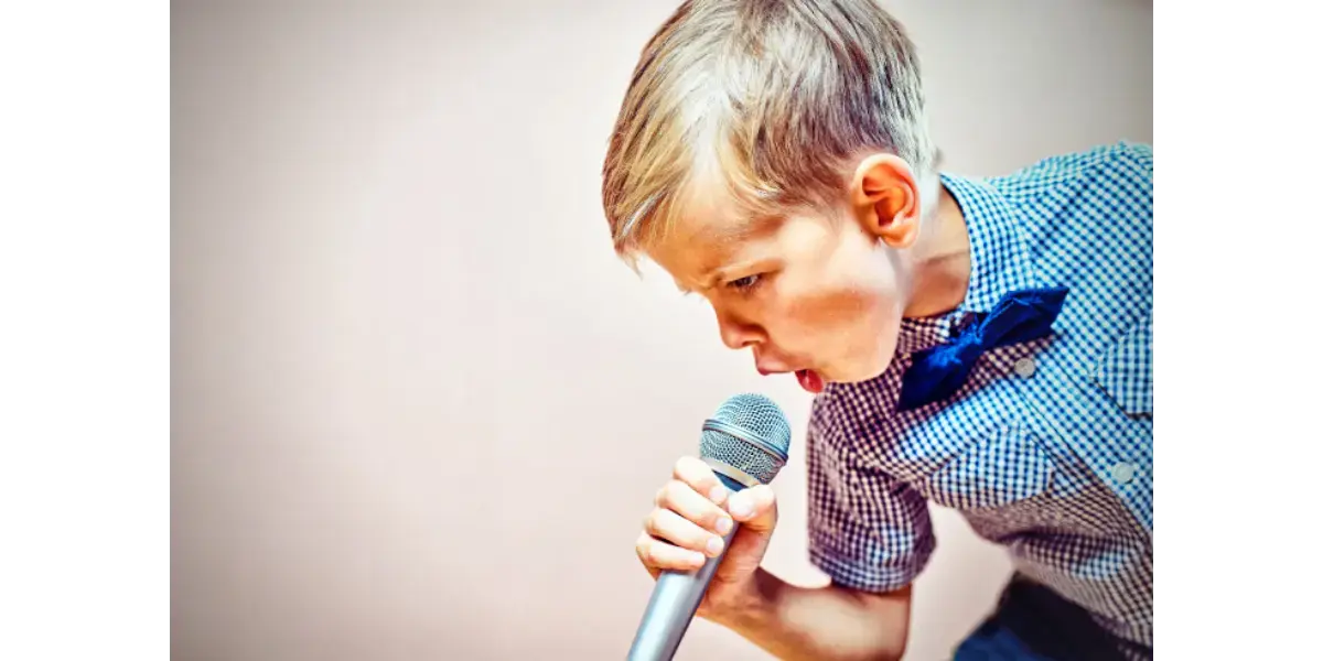 Young boy singing into a microphone to represent the chest voice register and vocal power techniques.