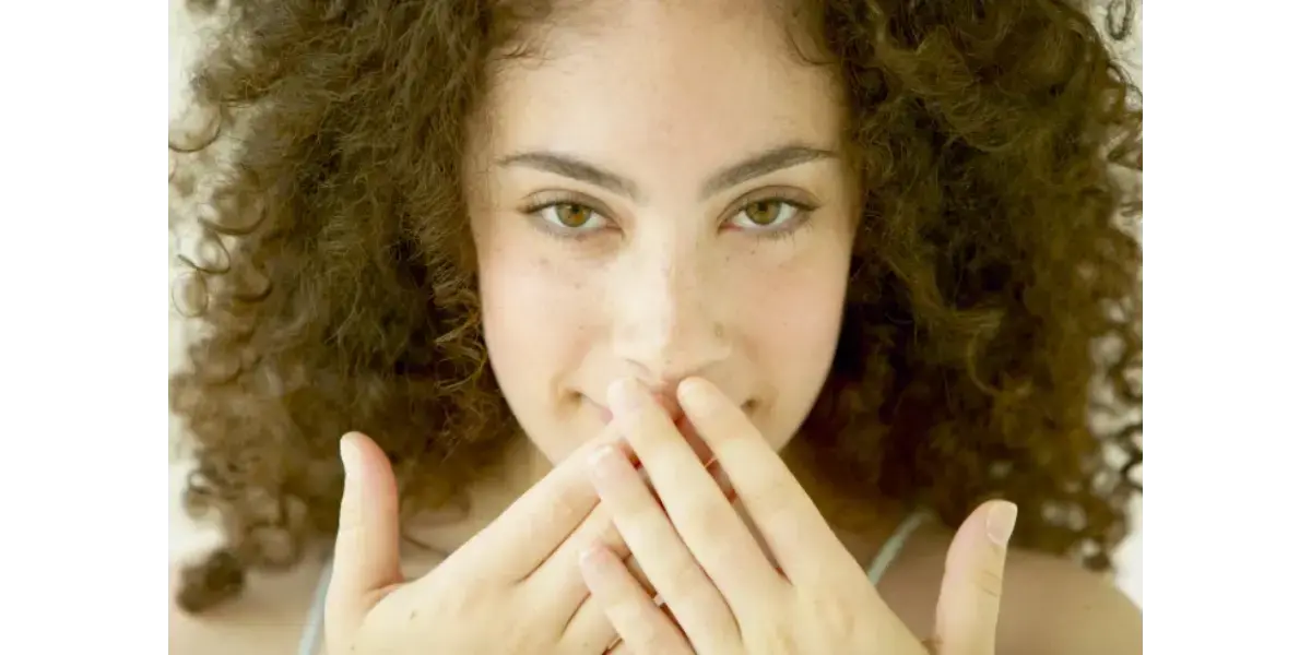 Close-up of a singer with hands on her neck, representing throat tightening and vocal constriction.