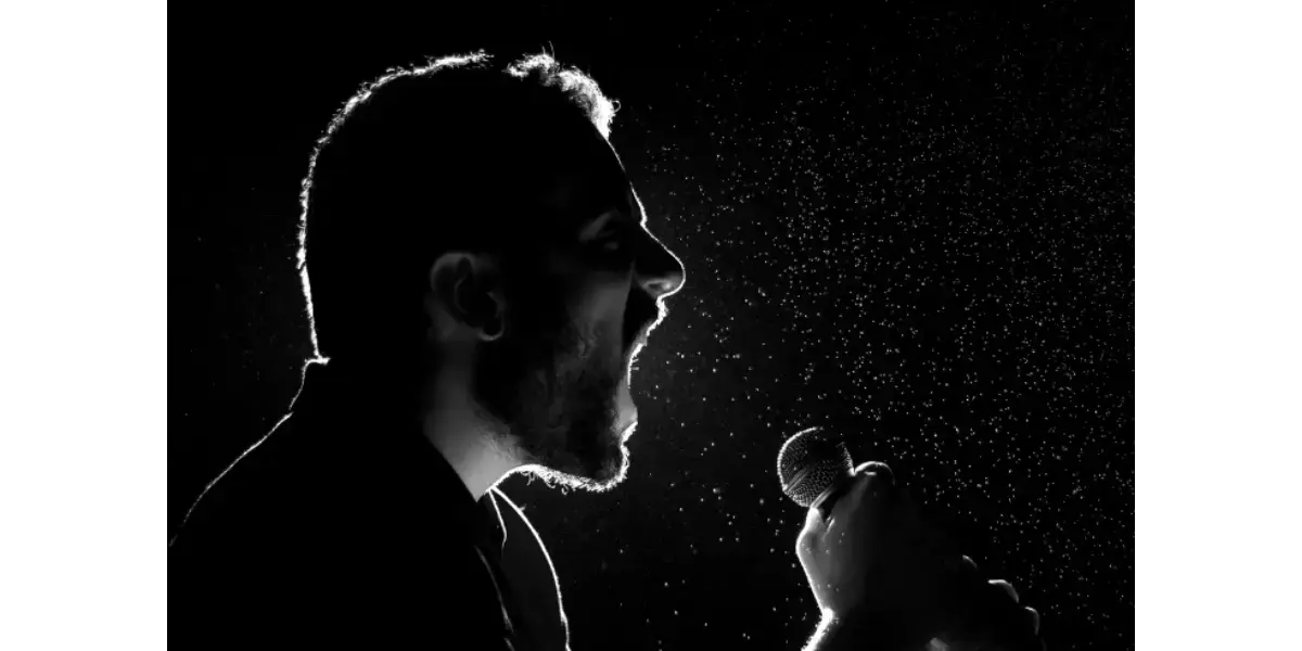 A silhouette of a singer at a microphone, illustrating the concept of controlled breathing and tension-free vocal mechanics.