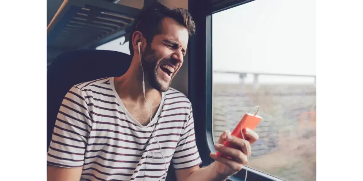 Man singing passionately while holding a smartphone and headphones