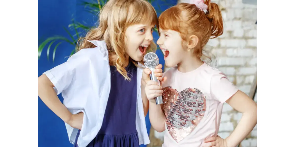 Two young children happily singing into a microphone, representing kids' singing lessons and vocal health.