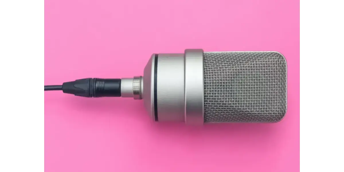 A vocal microphone on a pink background, illustrating vocal training and finding equilibrium between registration, breath, and placement.
