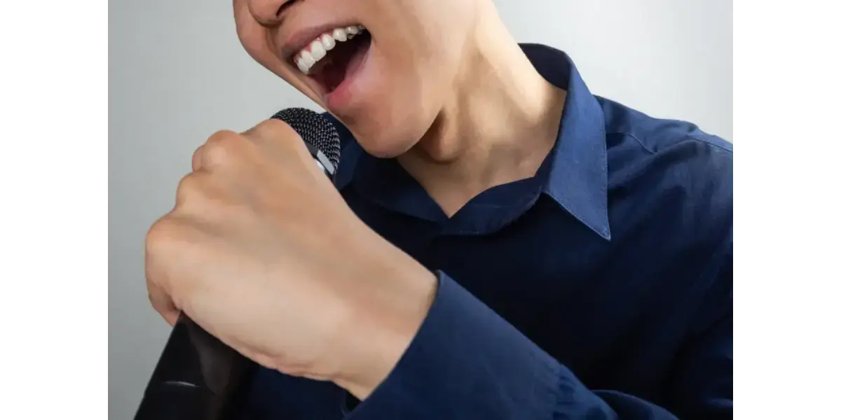 A singer touching their larynx to feel vocal cord vibrations while practicing healthy vocal techniques.