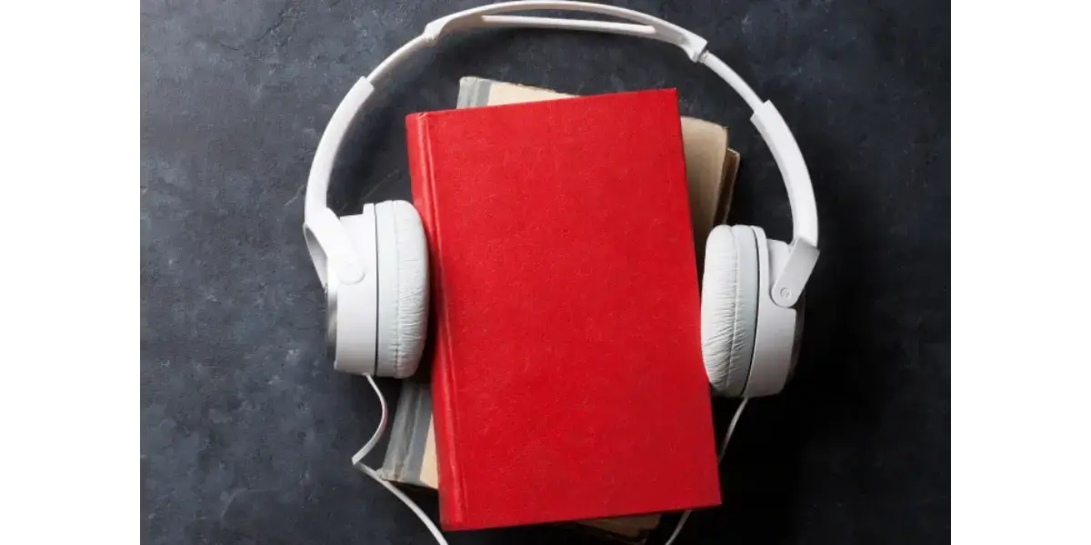 White headphones resting on a red notebook, representing vocal study, audio learning, and mental concepts.